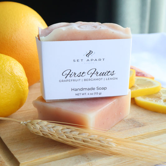 Bar of soap with a label on a wooden board with fruits and wheat.